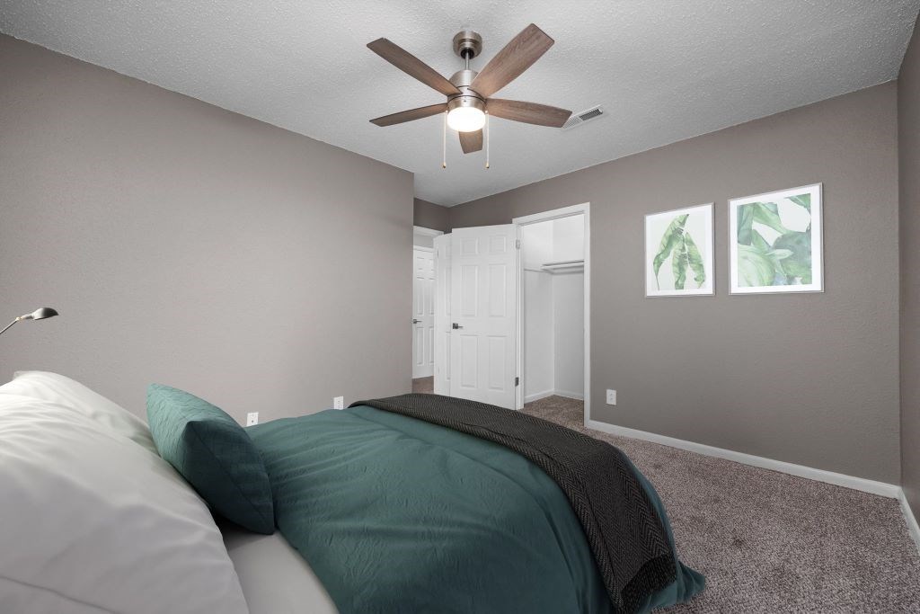 A bedroom with a bed, pillows, and a ceiling fan.