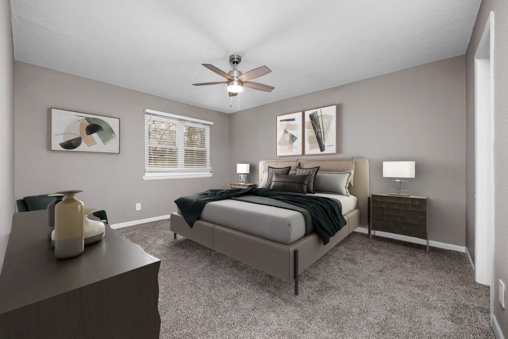 A bedroom with a bed, nightstand, and a ceiling fan.