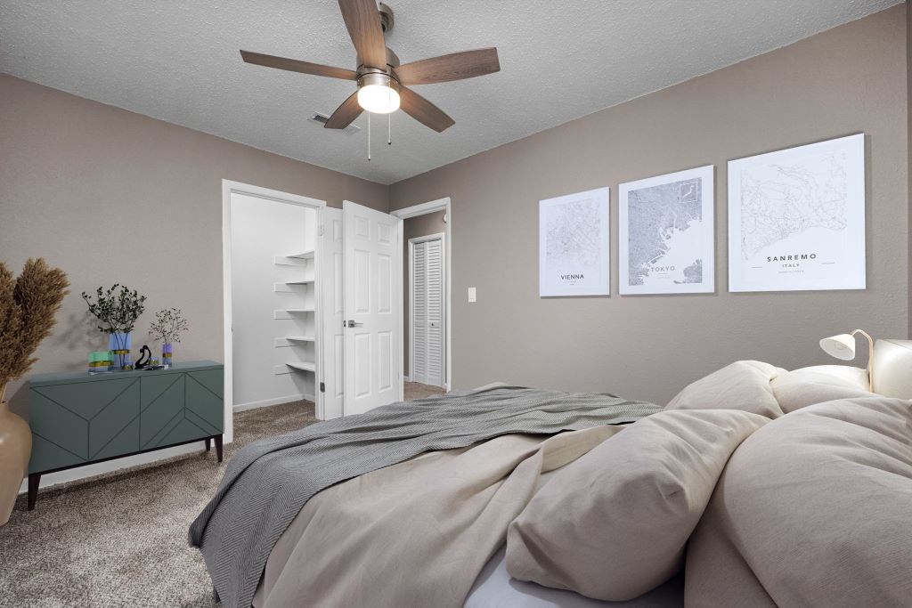 A bedroom with a bed, a dresser, and a ceiling fan.