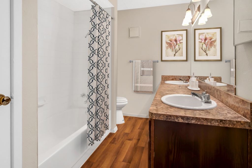 A bathroom with a marble countertop and a shower with a patterned curtain.