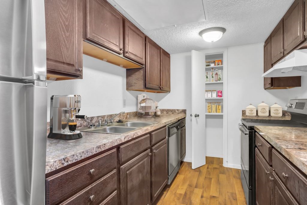 A kitchen with brown cabinets and a marble countertop.