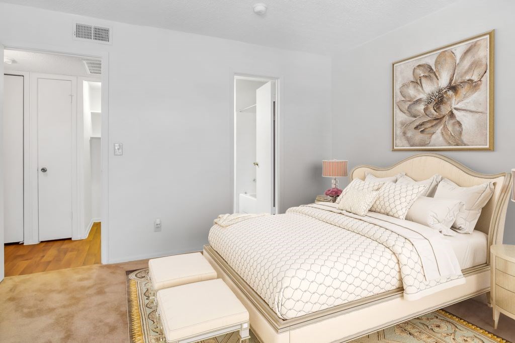 A bedroom with a large bed and a painting on the wall.