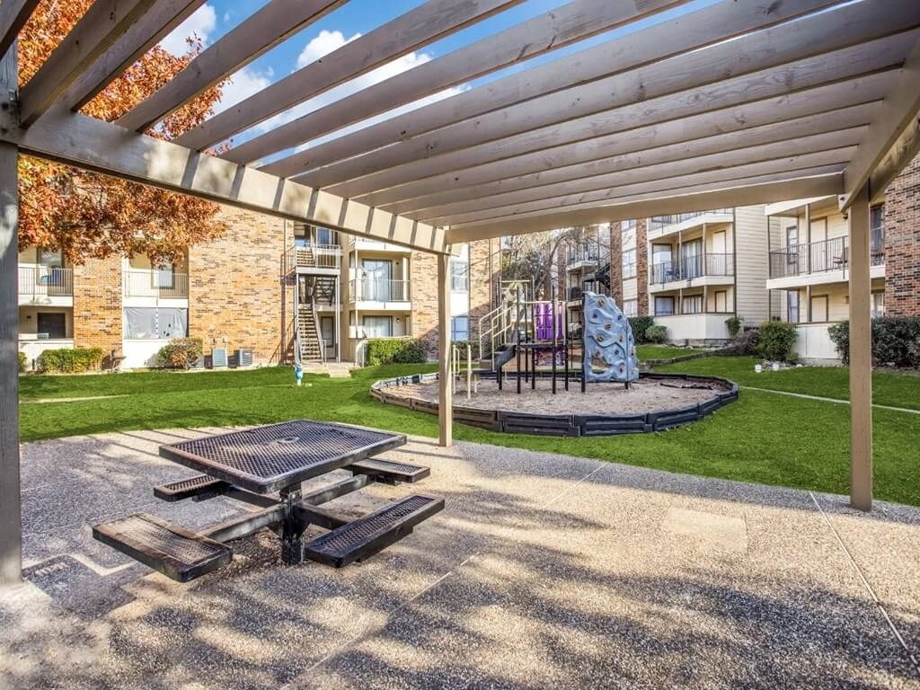 an outdoor patio with a picnic table and a playground