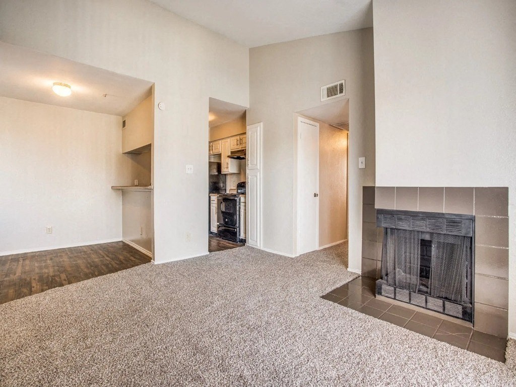 a living room with a fireplace and a kitchen in the background