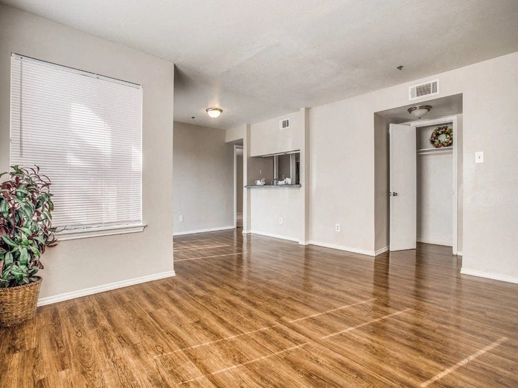 an empty living room with a hard wood floor and a window