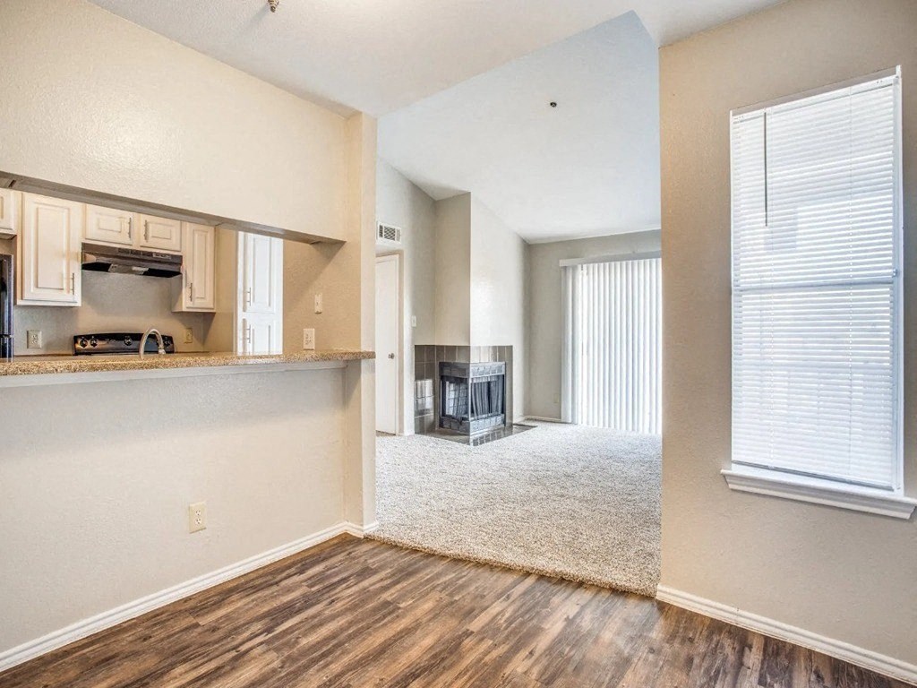 an empty living room with a kitchen and a fireplace