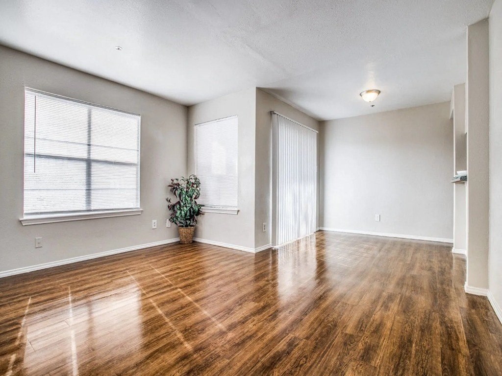 an empty living room with wood floors and a window