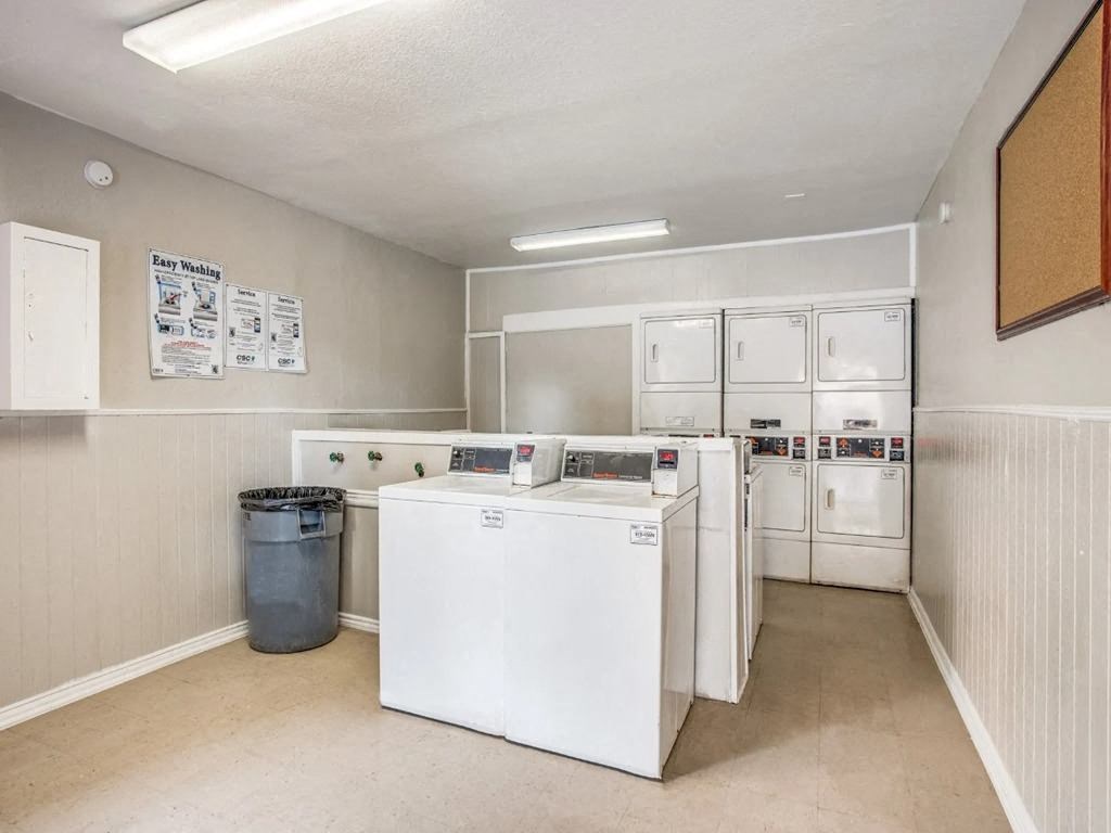 a kitchen with white appliances and a trash can
