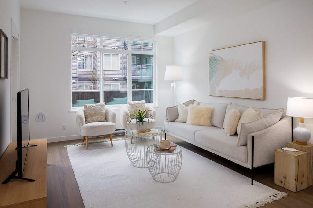 A living room with a white couch, a chair, a table, and a painting on the wall.