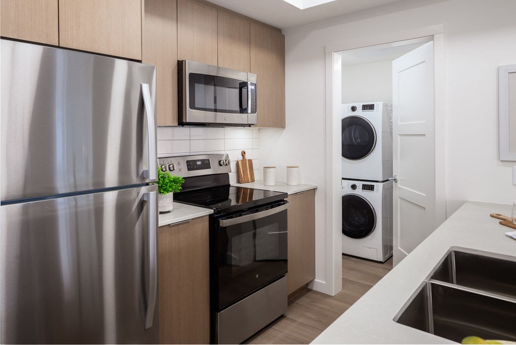 A modern kitchen with a stainless steel refrigerator and a microwave above the oven.