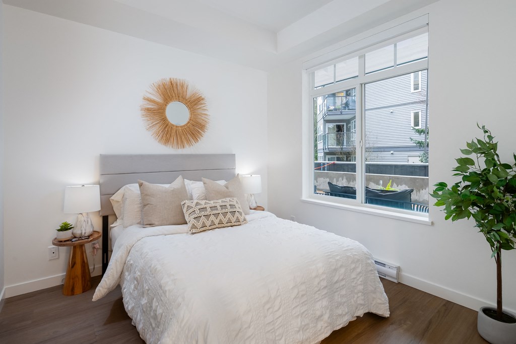 A bedroom with a large bed and a window overlooking a balcony.