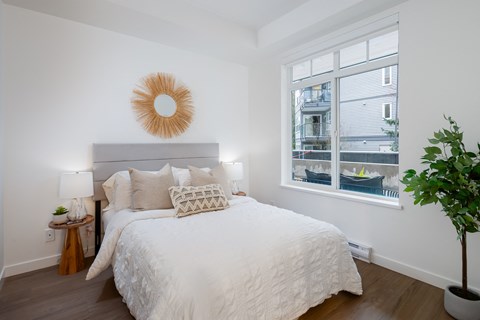 A bedroom with a large bed and a window overlooking a balcony.