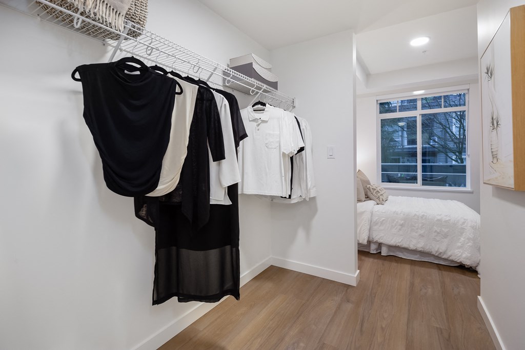 A white bedroom with a clothes rack and a bed.