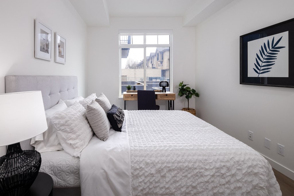 A bedroom with a large bed and a window overlooking a cityscape.