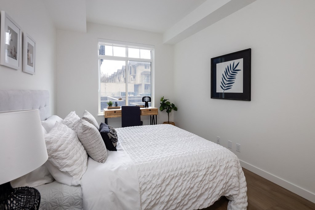 A bedroom with a large bed and a window overlooking a cityscape.