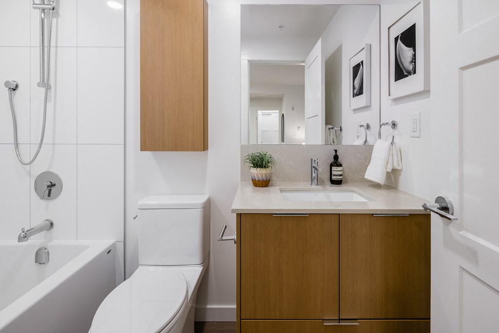 A white toilet sits next to a white bathtub in a bathroom.