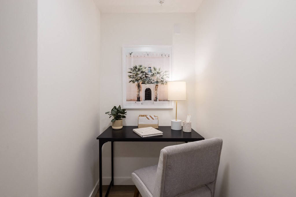 A small table with a chair and a picture on the wall.