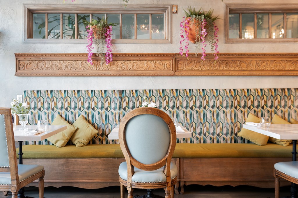 A restaurant with a green couch and wooden chairs.