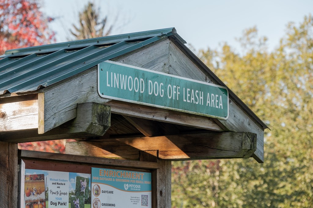 A sign for Linwood Dog Off Leash Area is displayed on a wooden structure.