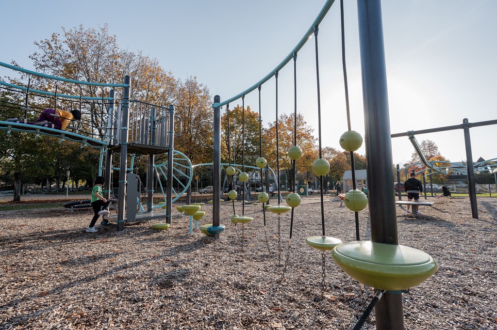 A playground with a swing set and a child playing on it.