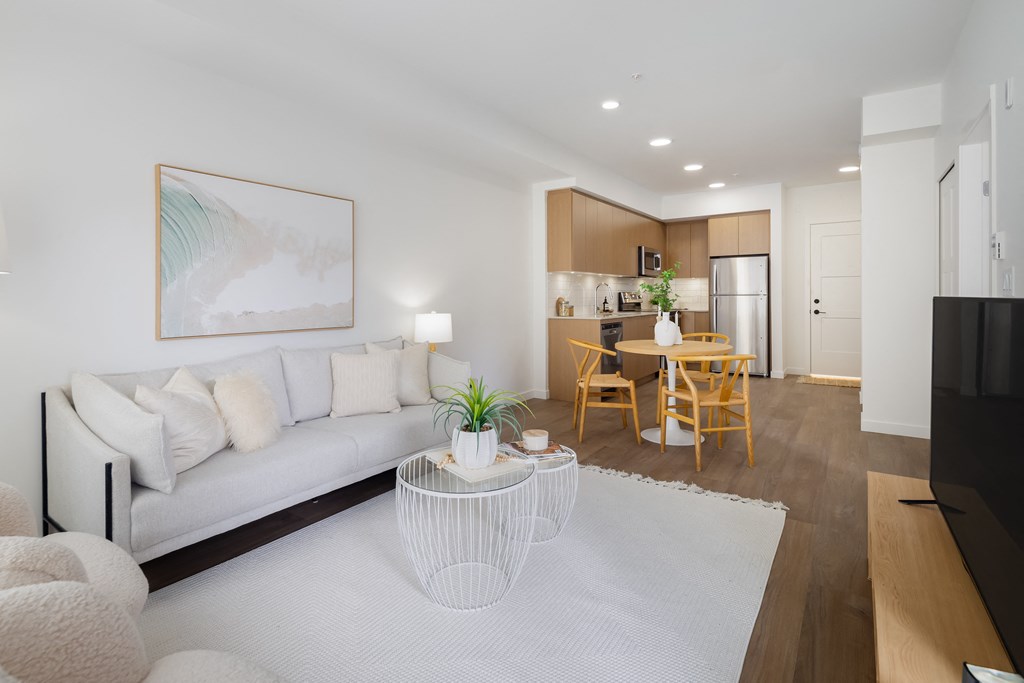 A modern living room with a white sofa, a coffee table, and a painting on the wall.