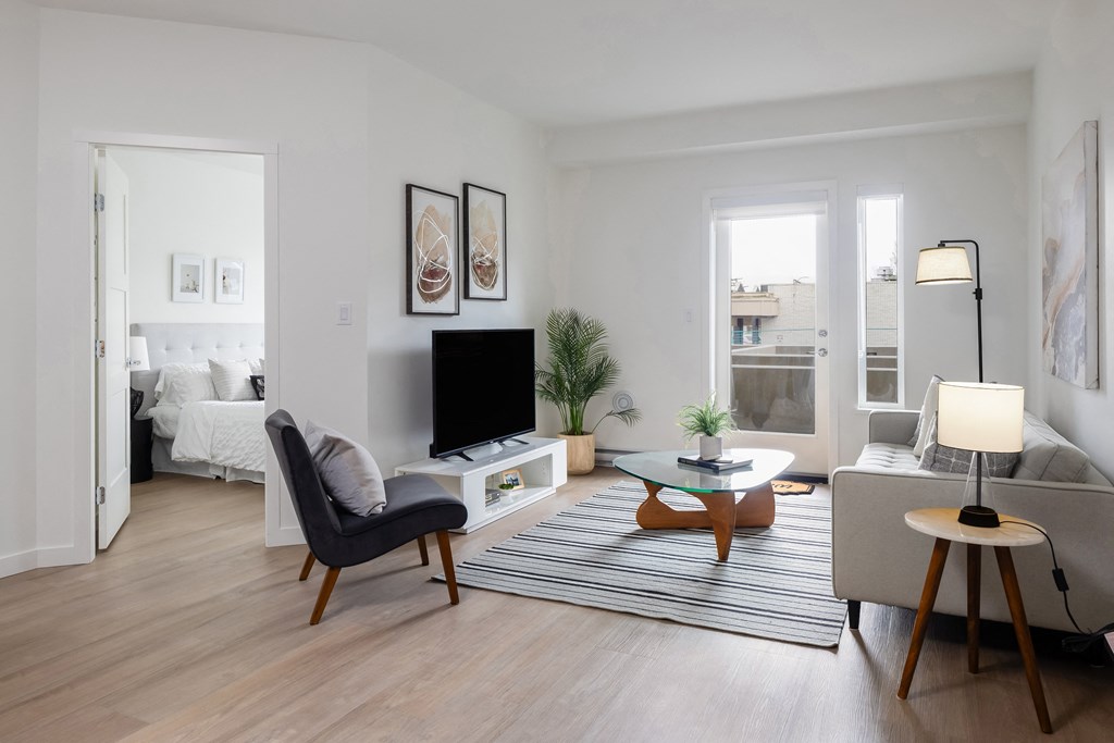 A living room with a black chair, a white sofa, a wooden coffee table, and a television.