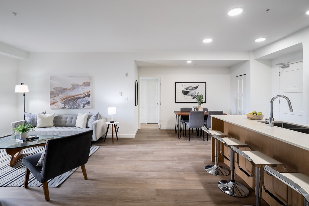 A modern kitchen with a black chair and a wooden floor.