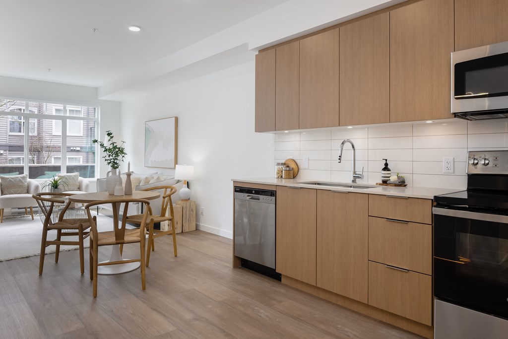 A modern kitchen with wooden cabinets and a dining table.