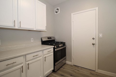 a kitchen with white cabinets and a stove and a door