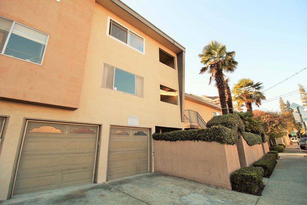 a building with a garage and palm trees in front of it