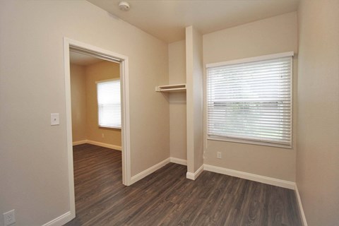 a bedroom with a closet and a window and wood flooring
