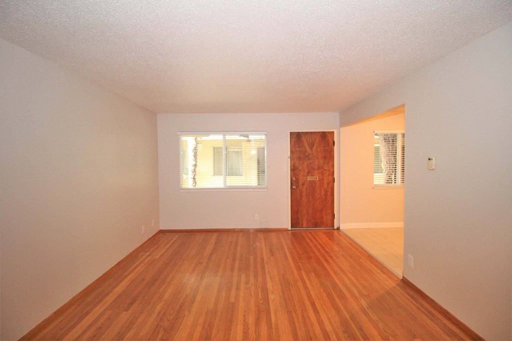 an empty living room with wooden floors and a wooden door