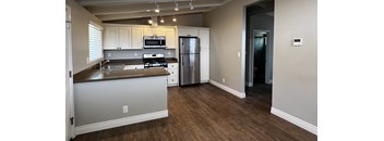 an empty kitchen with stainless steel appliances and white cabinets