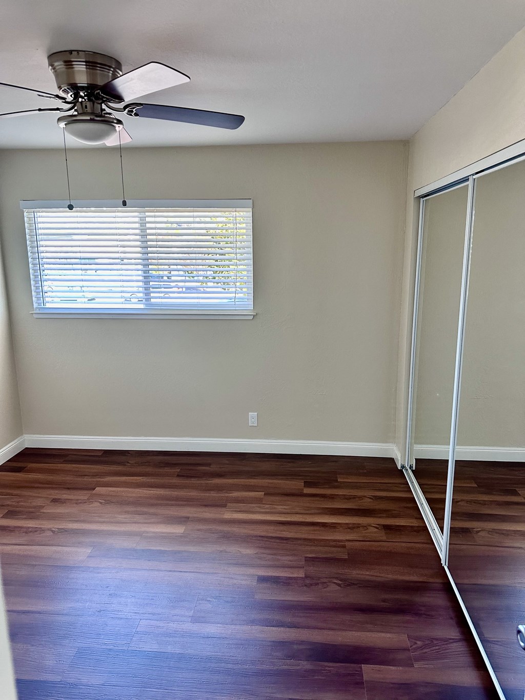 an empty room with wooden floors and a ceiling fan