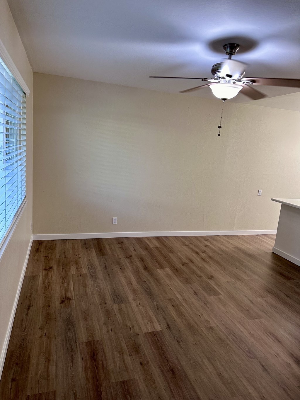 an empty living room with wood flooring and a ceiling fan