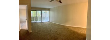 the living room of an empty house with a ceiling fan