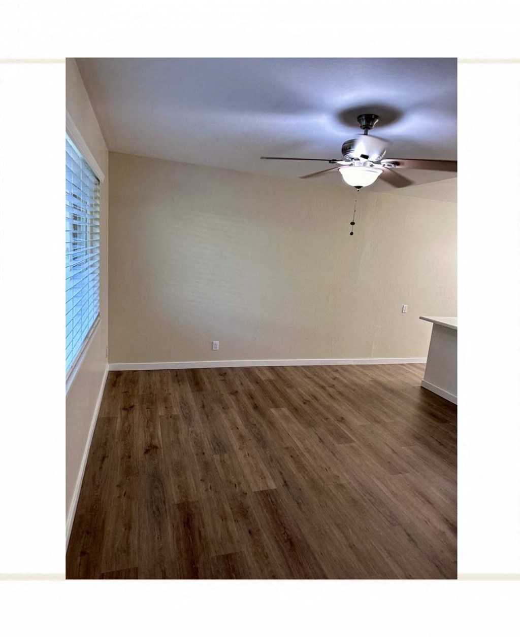 an empty living room with a ceiling fan and a window