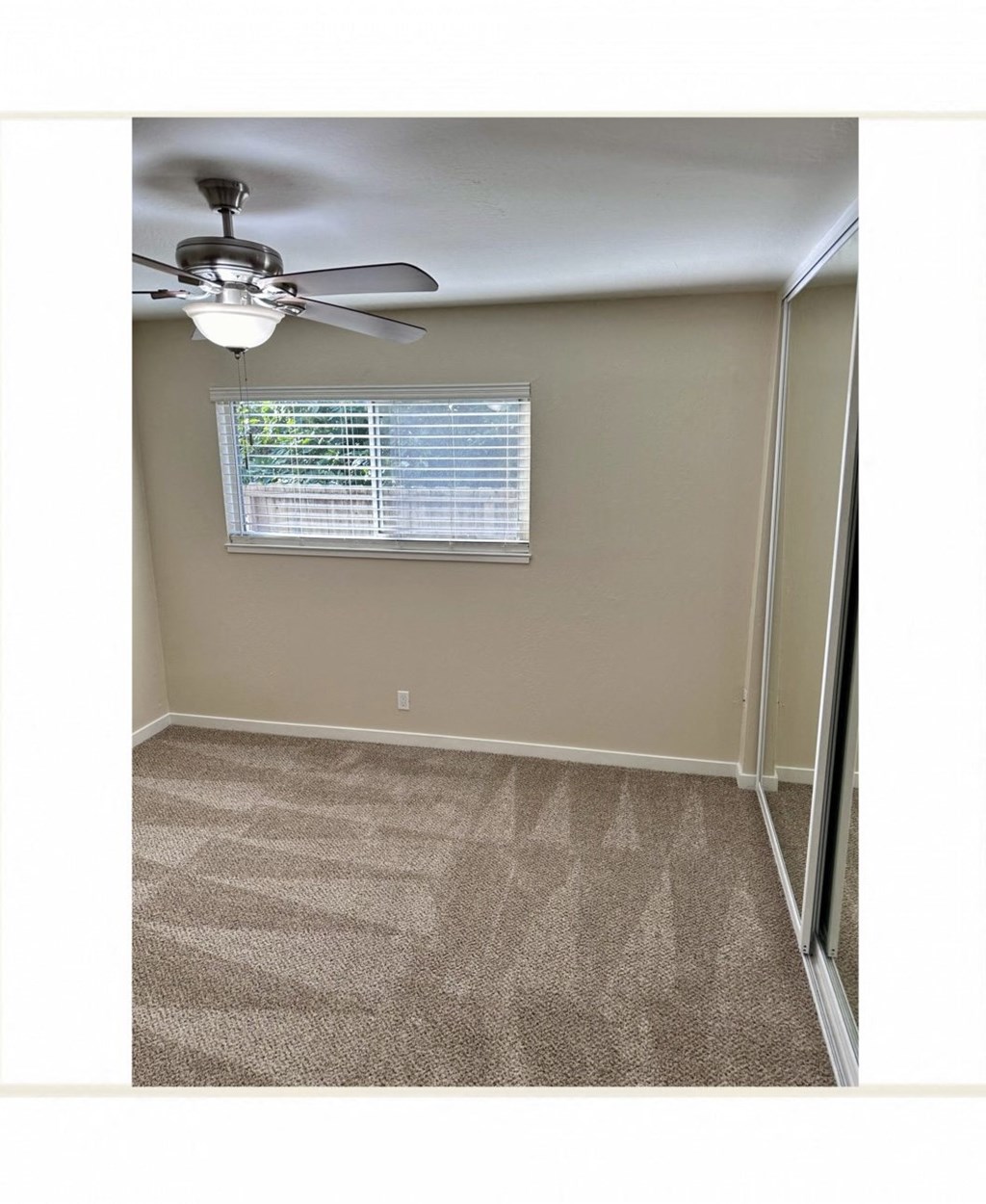 an empty bedroom with a ceiling fan and a window