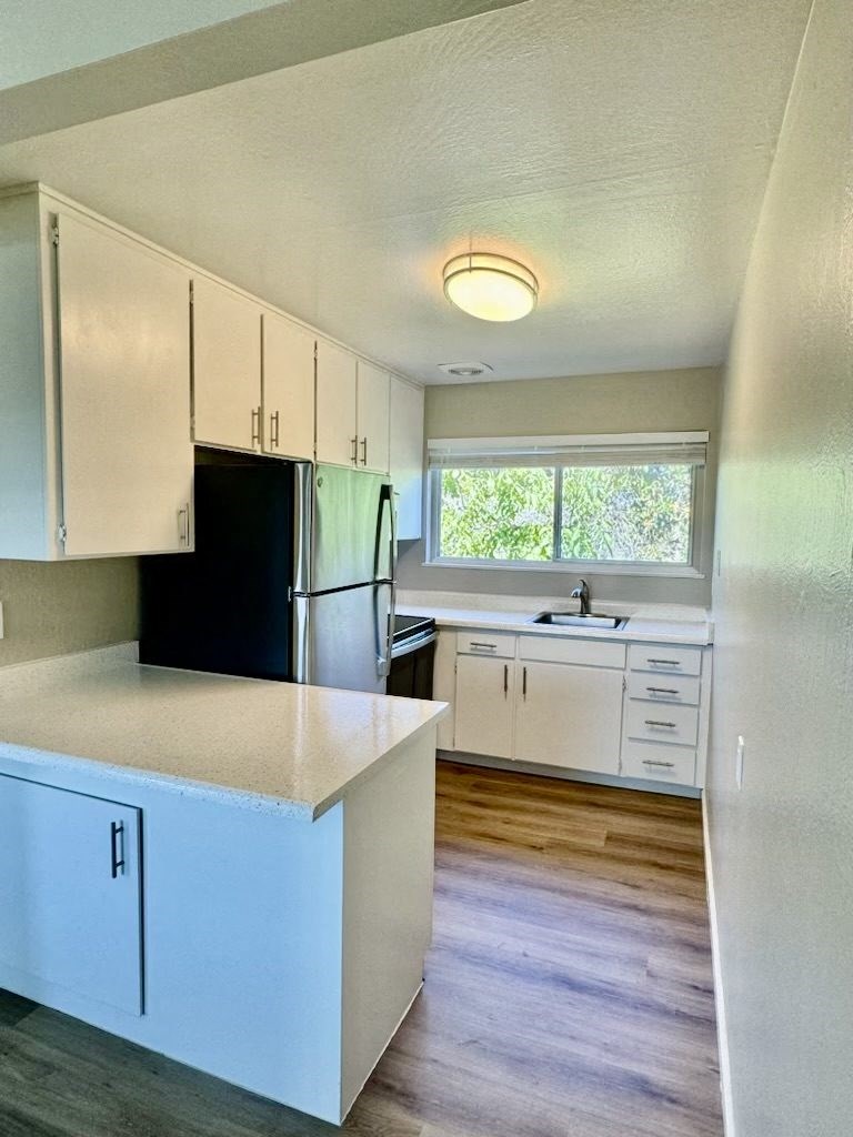 an empty kitchen with white cabinets and a black refrigerator