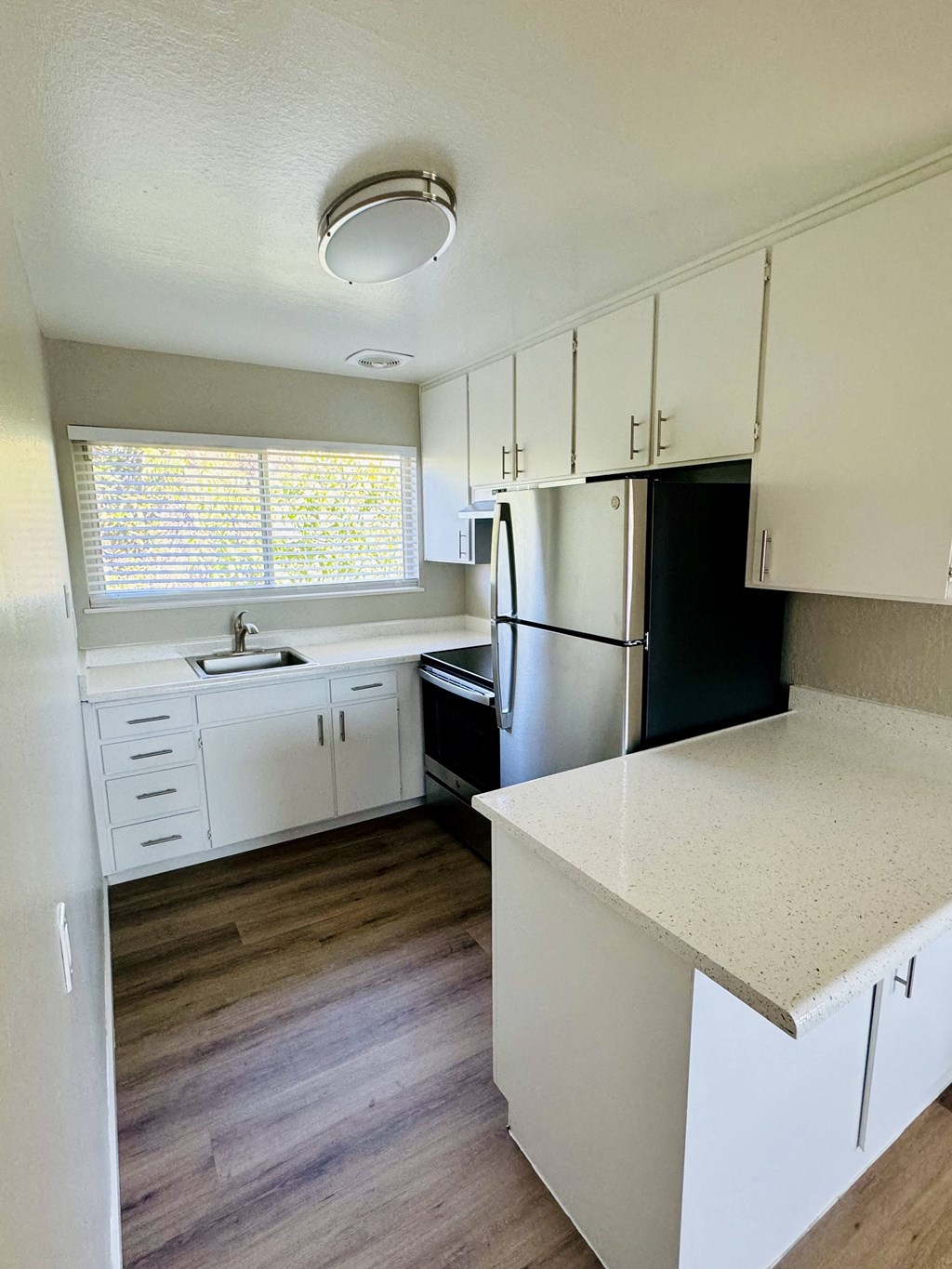 an empty kitchen with white cabinets and a black refrigerator