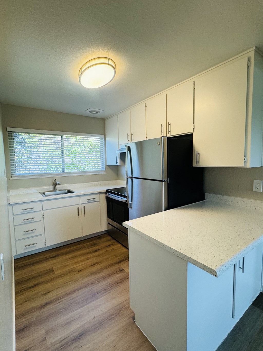 an empty kitchen with white cabinets and a black refrigerator