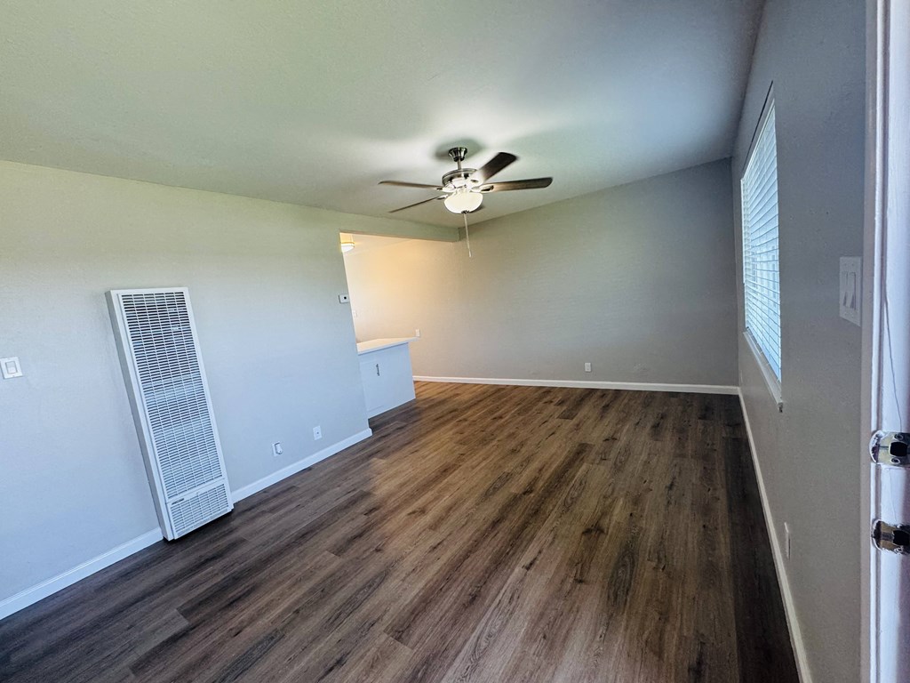 an empty living room with wood flooring and a ceiling fan