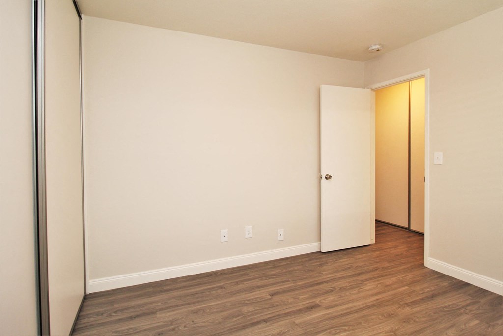 a bedroom with wood flooring and a door to a closet