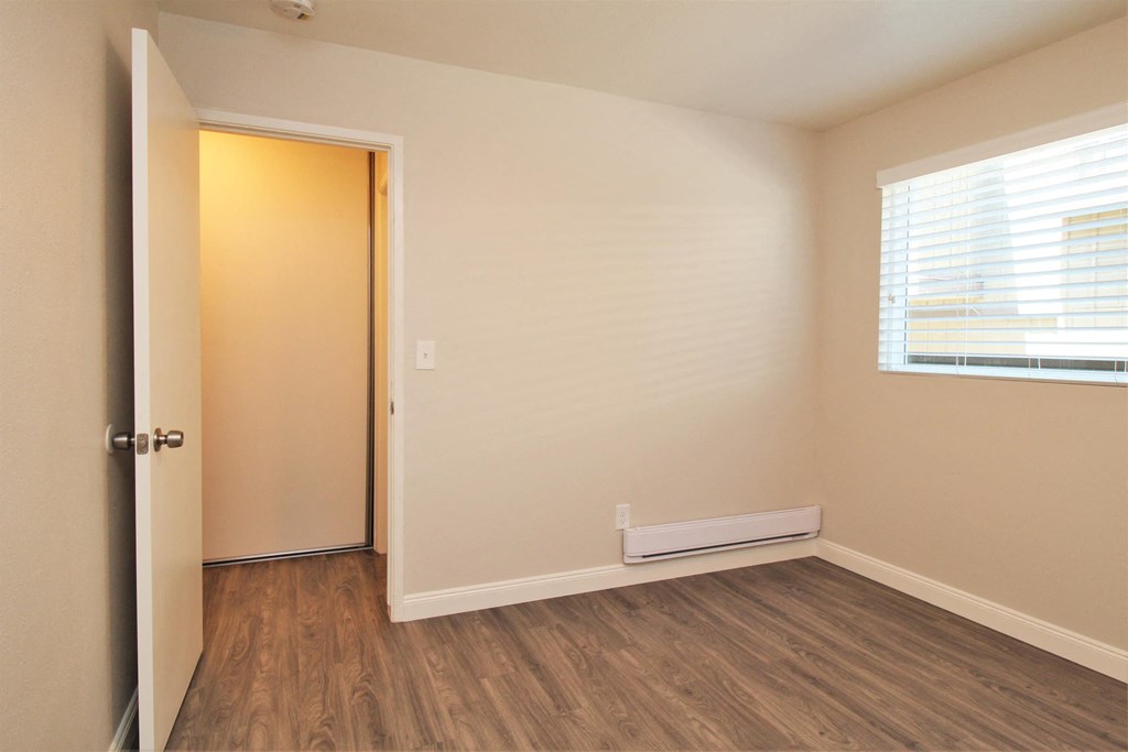 a bedroom with wood flooring and a door to a closet