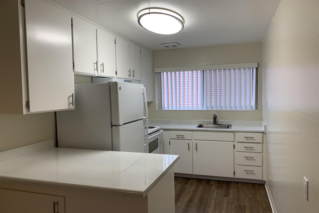 an empty kitchen with white cabinets and a window