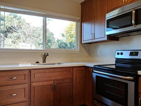 a kitchen with a stove and a sink and a window