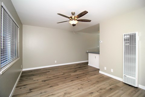 an empty living room with wood floors and a ceiling fan