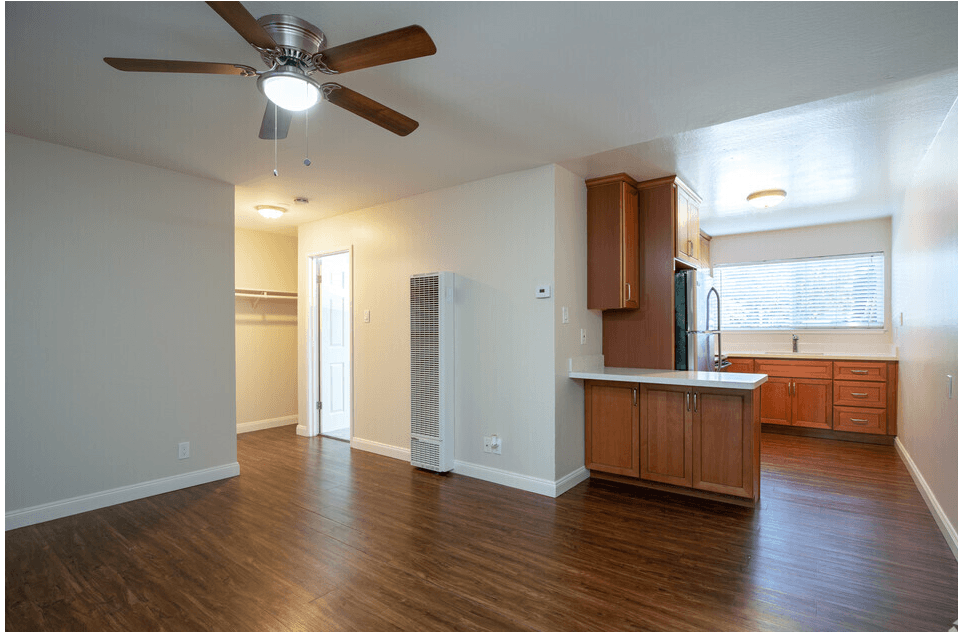 an empty living room and kitchen with a ceiling fan