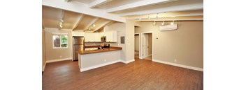 an empty living room and kitchen with a wood floor