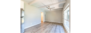 an empty living room with wood floors and a ceiling fan